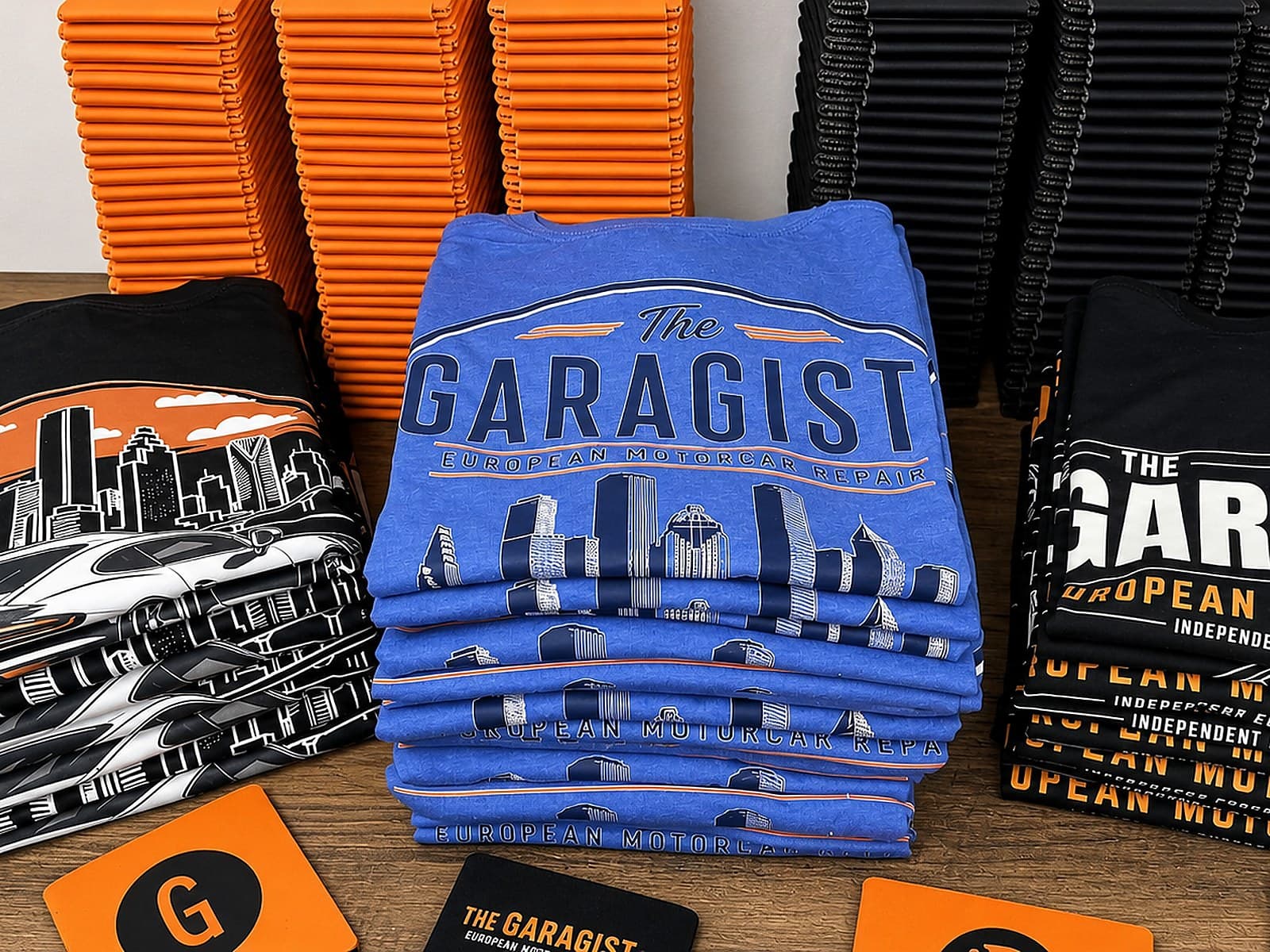 Garagisti shirts, koozies, stickers, and orange cards arranged together